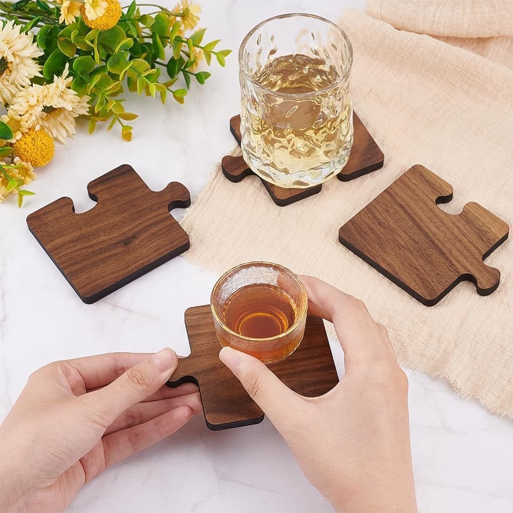 Wooden puzzle piece coasters holding drinks on a marble surface, with flowers in the background.
