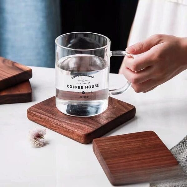 Clear glass mug with water on a square wooden coaster; simple, elegant design