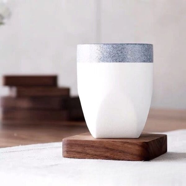 White ceramic cup with gray textured top on a wooden coaster