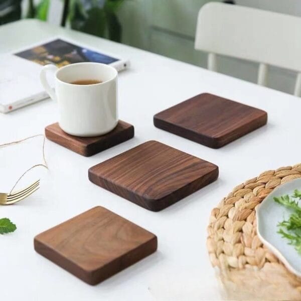 Wooden coasters on white table with tea, fork, book, and woven plate.