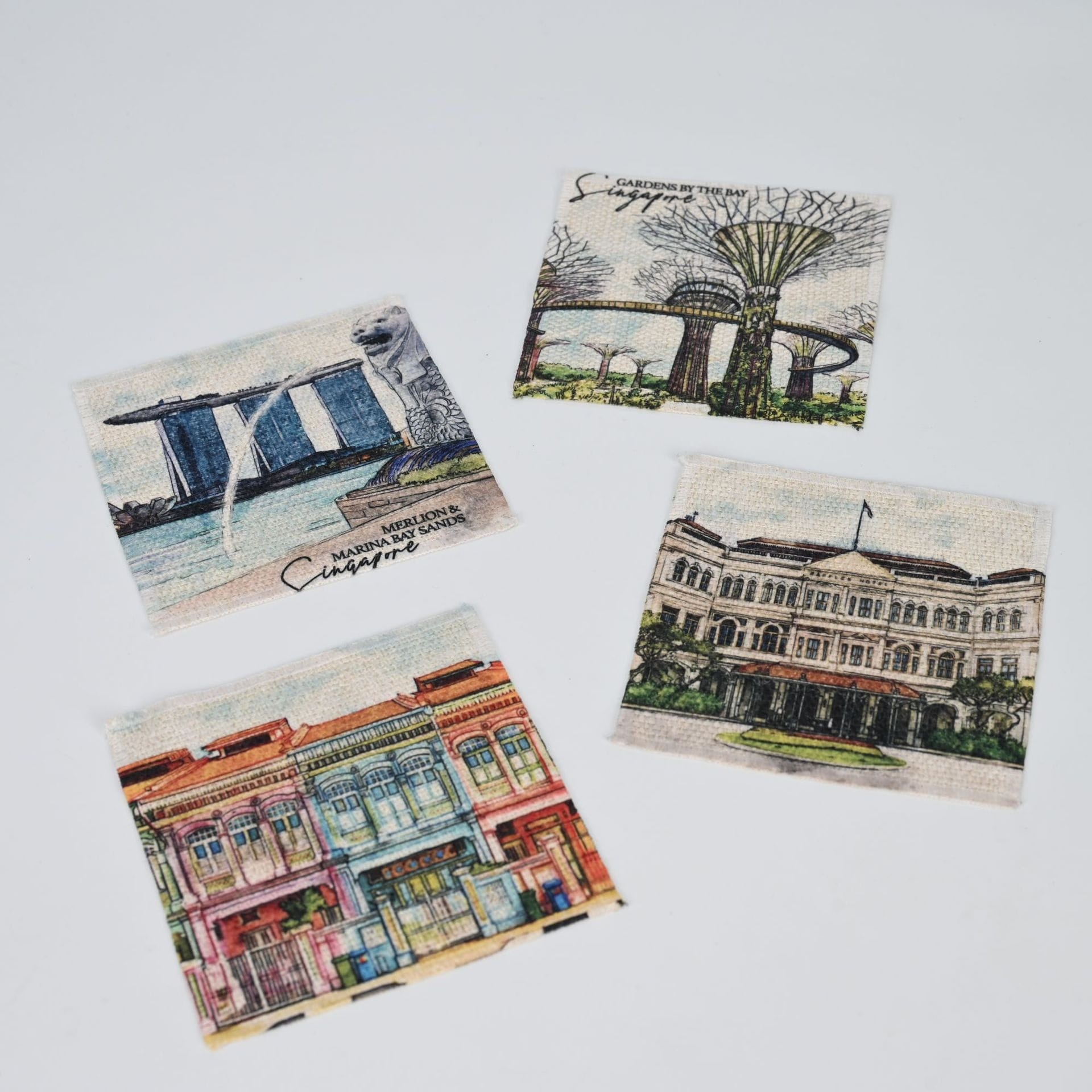 AUTO-DRAFT coasters featuring Singapore landmarks: Merlion, Gardens by the Bay, Fullerton Hotel, and shophouses.
