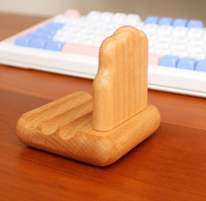 Wooden Animal Phone Wood Holder: A handcrafted phone wood holder on a desk, next to a keyboard.