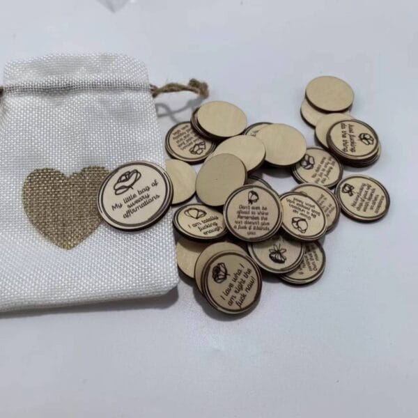 AUTO-DRAFT: Canvas bag with heart design and wooden tokens printed with sweary affirmations scattered around.