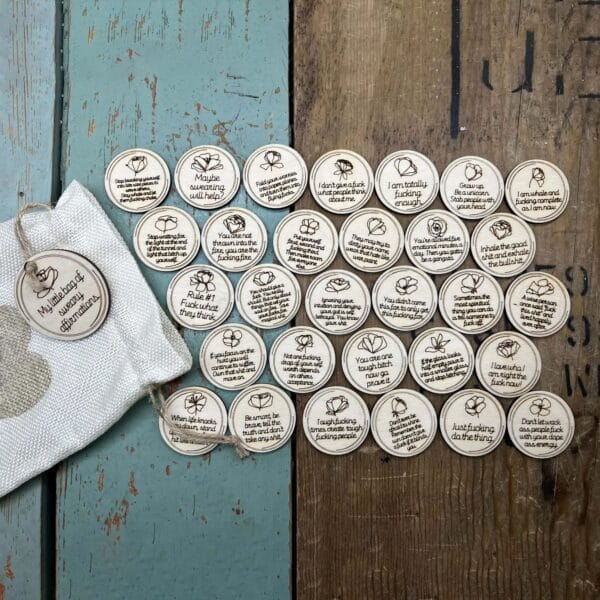 Sweary Affirmations: Wooden discs with funny, empowering quotes in a drawstring bag for self-love and motivation.