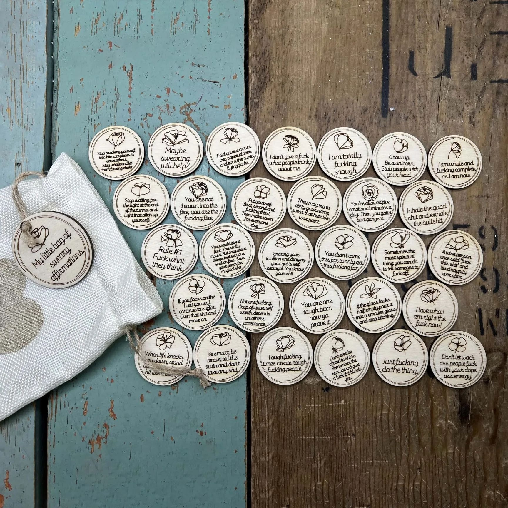 Sweary Affirmations: Wooden discs with funny, empowering quotes in a drawstring bag for self-love and motivation.