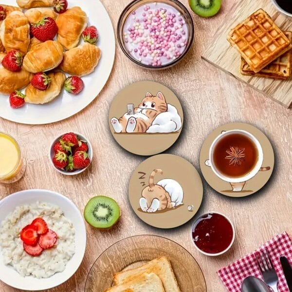 Breakfast scene with pastries, fruit, and cat-themed coasters featuring cartoon kittens relaxing and drinking tea.