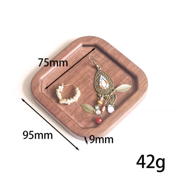 Wooden tray holding a beaded hoop earring and a vintage-style dangle earring with feathers and beads.