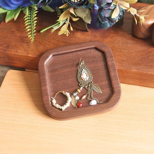 Square wooden tray displaying earrings and beaded jewelry