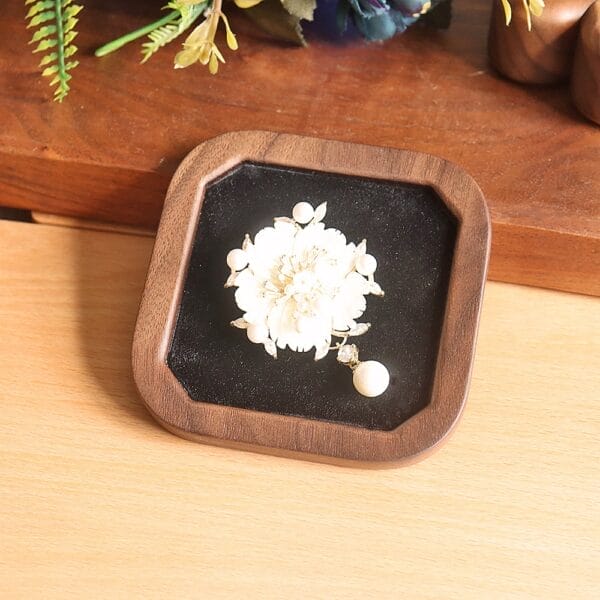 AUTO-DRAFT: Flower-shaped pearl brooch displayed on a dark velvet lined wooden stand