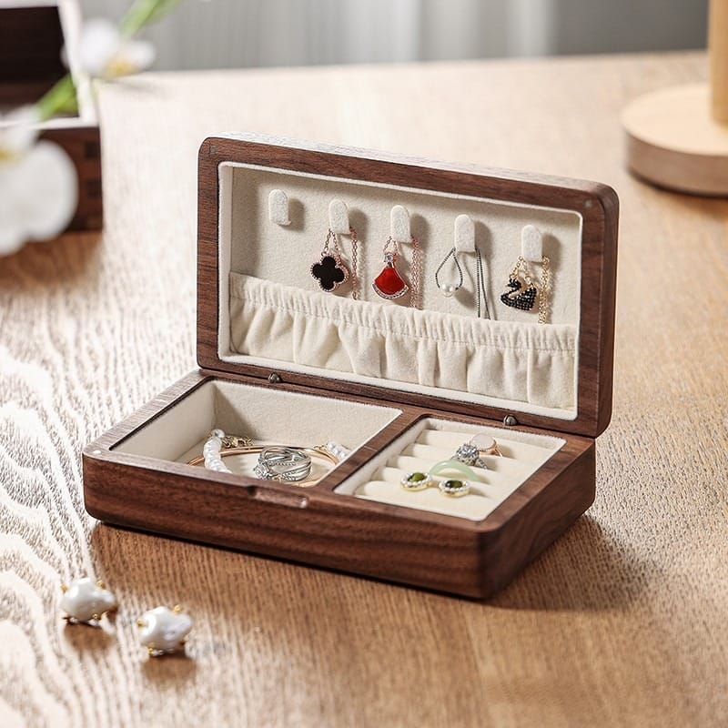Open wooden jewelry box with velvet lining showcasing necklaces, rings, and earrings.