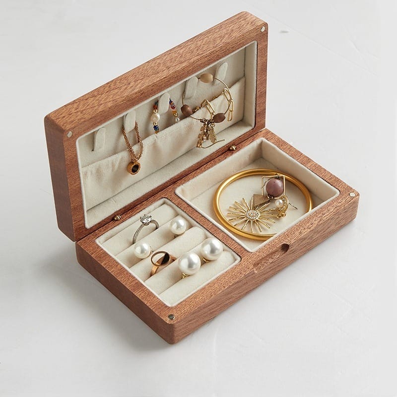 Wooden jewelry box with soft velvet lining displaying necklaces, earrings, and a bangle.