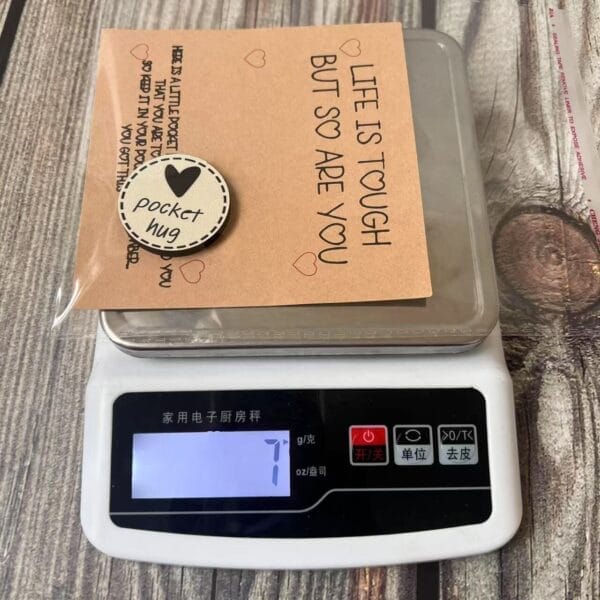 Pocket Hug token on a scale with encouraging message. Personalized wooden engraved coin for retail or event gifts.