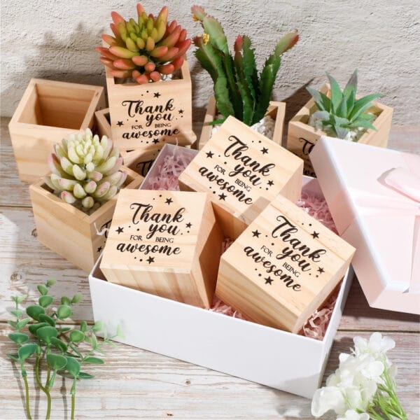 Wooden cubes with "Thank you for being awesome" text, succulents in wooden pots, and a white gift box with pink ribbon.