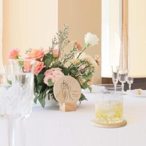 Wedding table setting: Floral centerpiece with personalized wooden sign featuring bride and groom