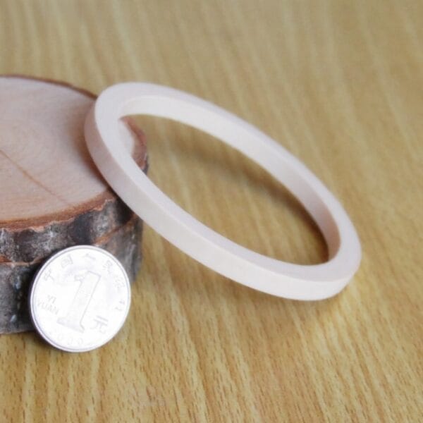 Unpainted Wooden Bangle: Raw wooden bracelet blank for DIY jewelry making, shown with coin for scale.