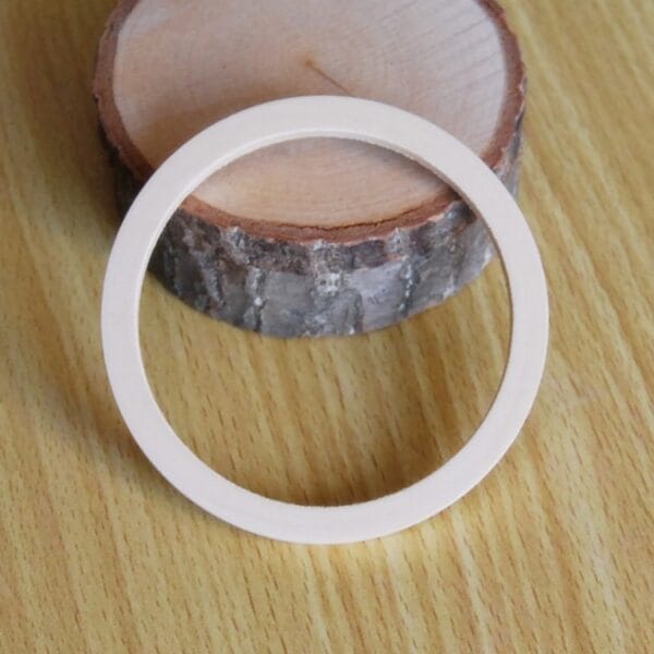 Unpainted Wooden Bangle: Raw wooden bracelet blank for DIY jewelry projects, shown on wood slice.