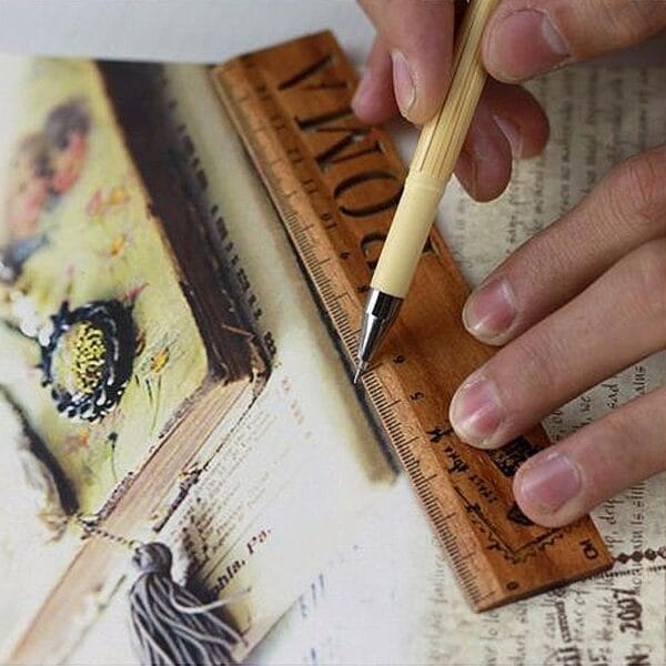 Hand using ruler and pen on book. AUTO-DRAFT may be related to the book's content.