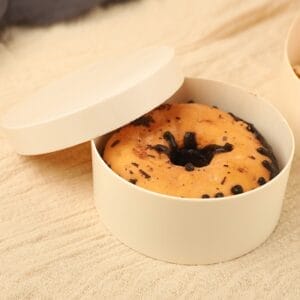 Donut in a round container with the lid partially open.