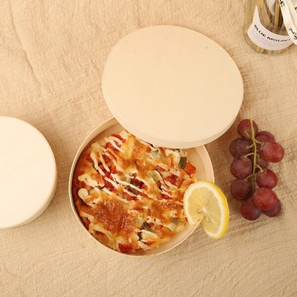 AUTO-DRAFT: Pizza in round wooden container with lid, alongside grapes and a lemon slice.