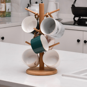 Wooden mug tree holding six ceramic mugs in various colors and patterns