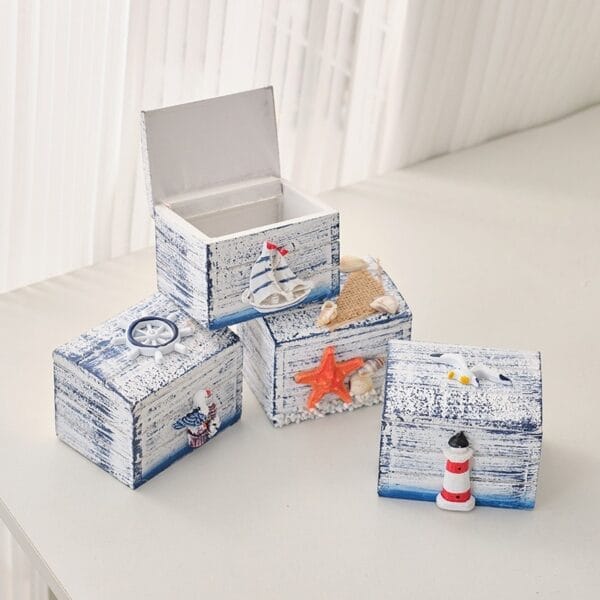 Nautical-themed wooden boxes featuring sailboat, starfish, lighthouse, and ship wheel decorations