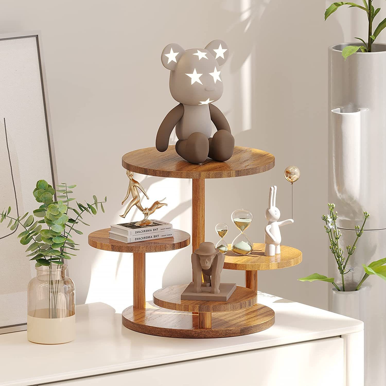 Tiered display stand with decorative objects: bear figurine, hourglass, rabbit, and greenery.