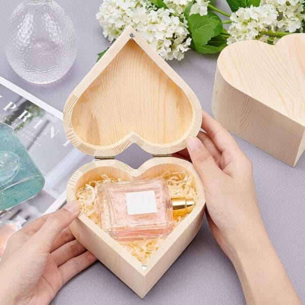 Heart-shaped wooden box with perfume inside, open to display contents.